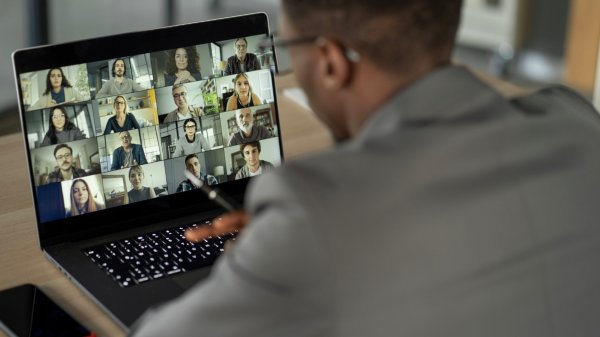 Image of a business man looking at a virtual meeting on a laptop screen. 